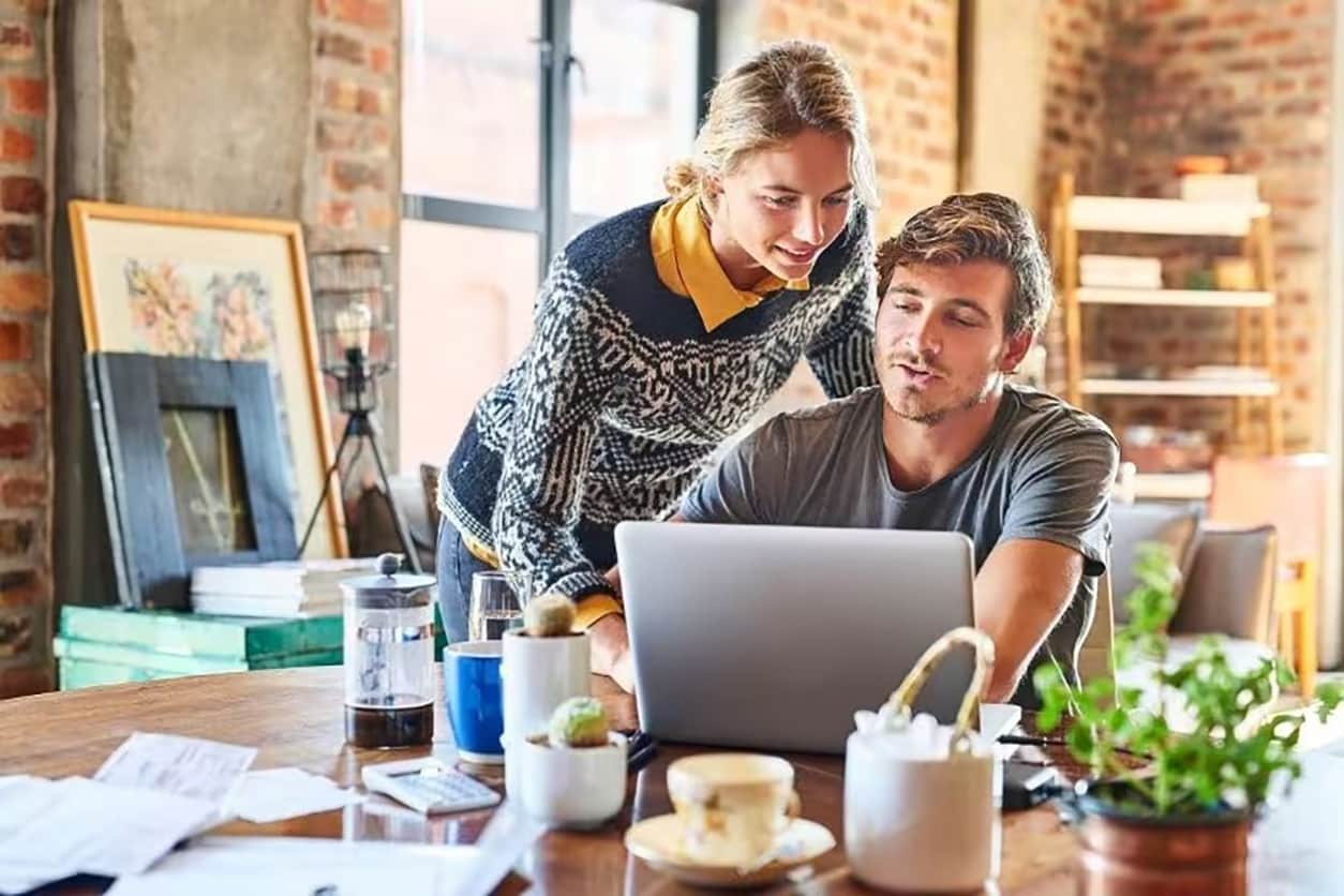 Man and woman are looking at a laptop in a room