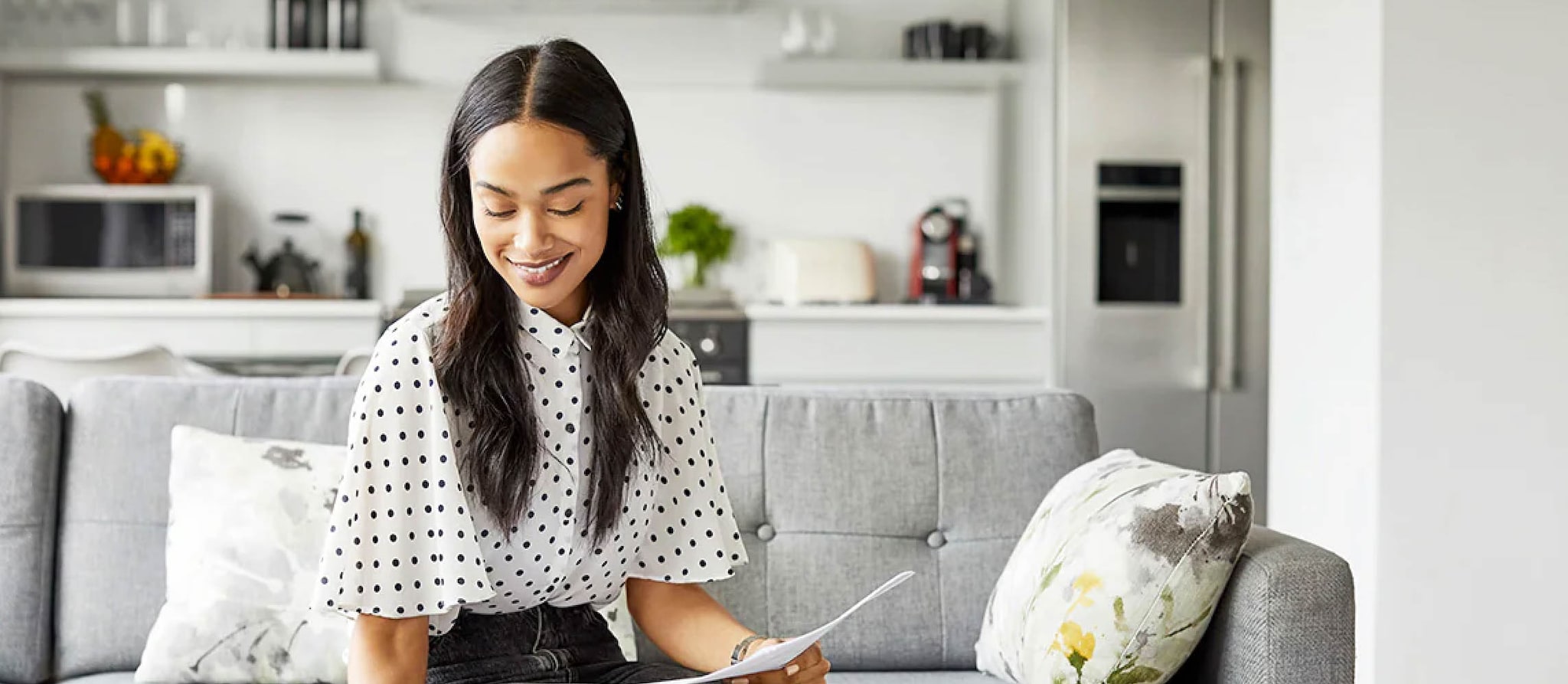A woman is sitting and working on a laptop on a sofa.