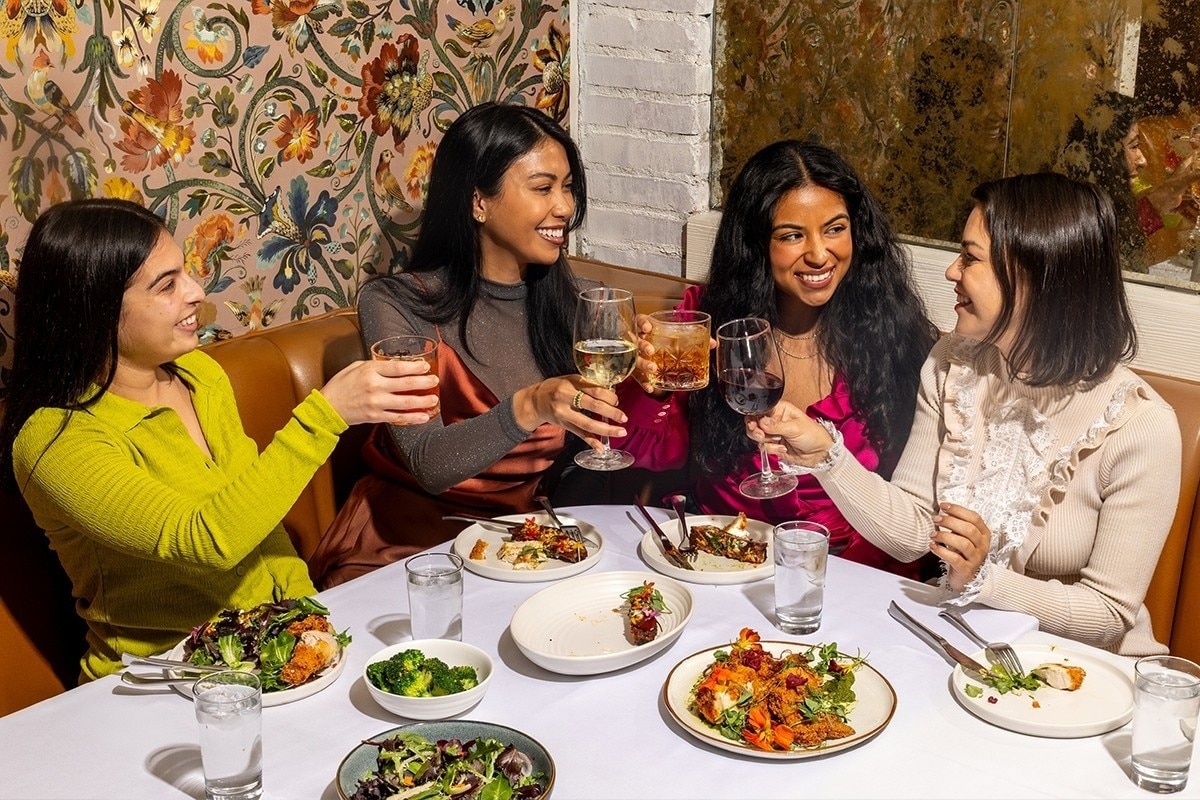 A group of friends in their 30s enjoying a meal at an upscale restaurant.