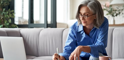 Woman on couch writing at coffee table