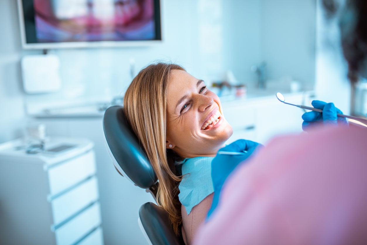 Woman is sitting in the dentist chair, smiling while looking at a doctor
