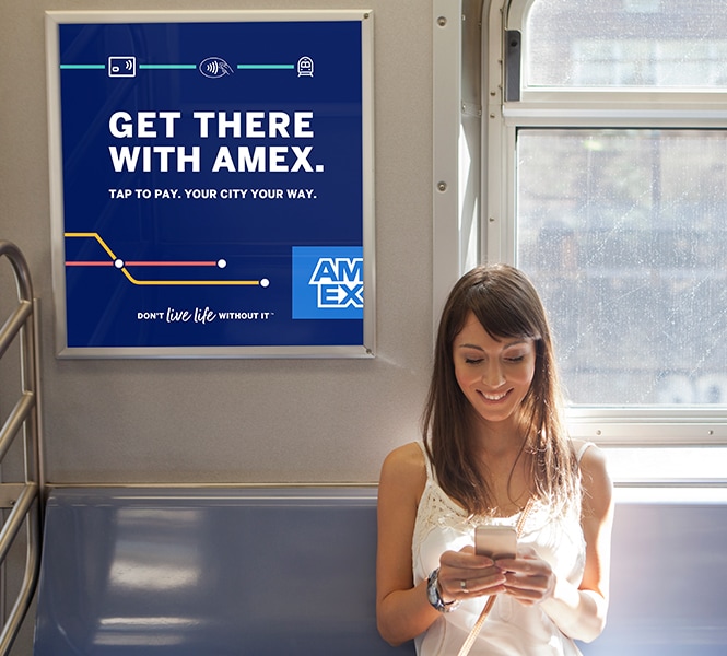 A woman seated on the subway smiling while looking at her phone