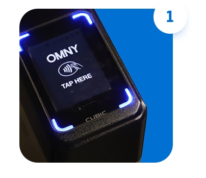 Subway turnstile screen displaying the OMNY logo, a contactless symbol, and the words "tap here"