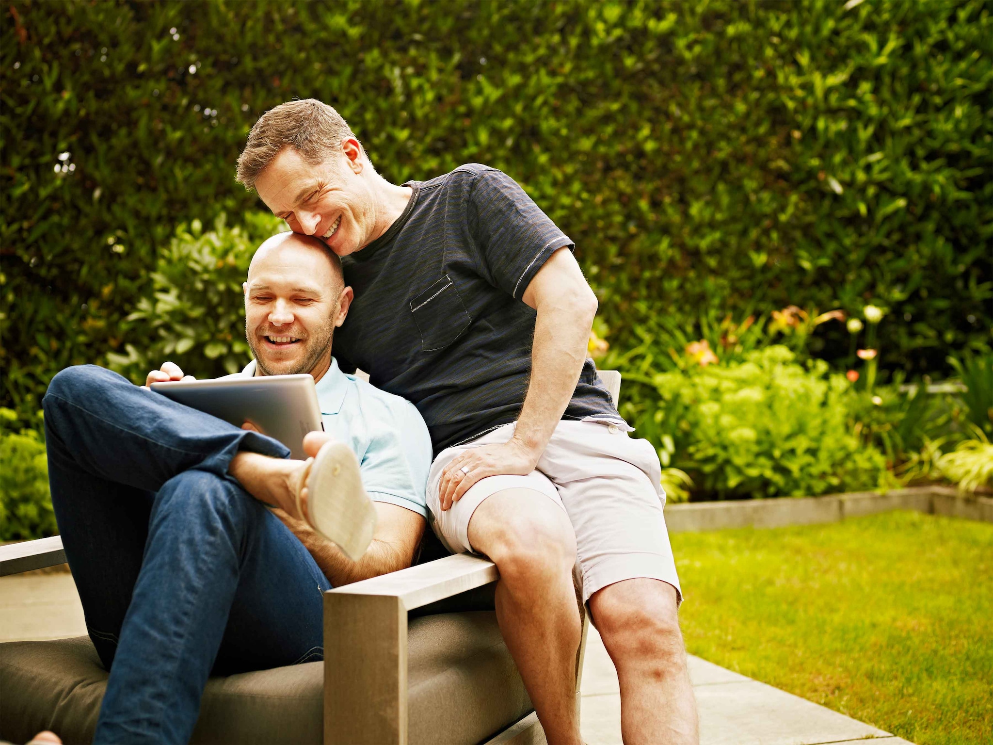 Two men sitting outside with a tablet device 
