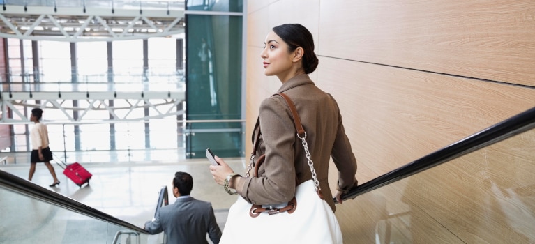 Woman riding down escalator