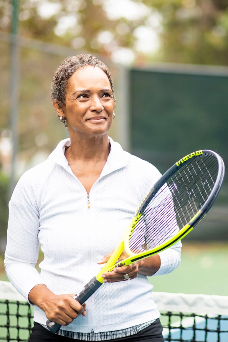 Mujer sonriente sosteniendo una raqueta de tenis en una cancha