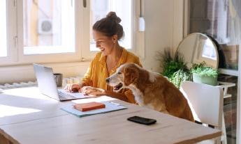 image of the lady working on laptop with a dog beside