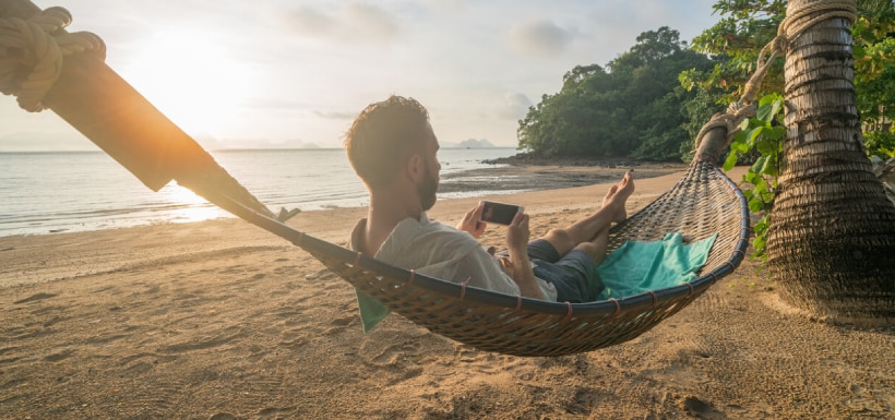 Un hombre en la playa consultando información desde su celular.