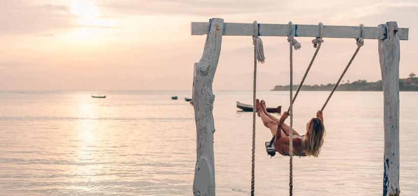 Una mujer en un columpio junto al mar.