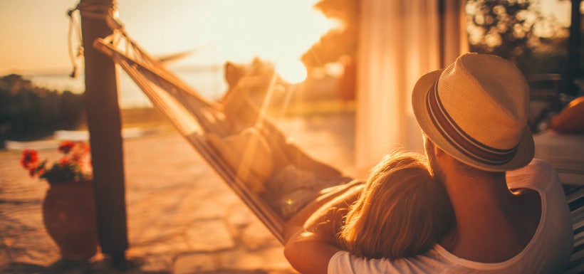 Una pareja acostados en una hamaca en una playa.