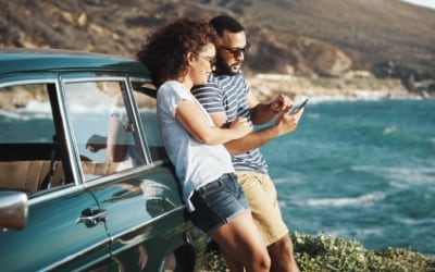 personas frente a un auto azul en la costa
