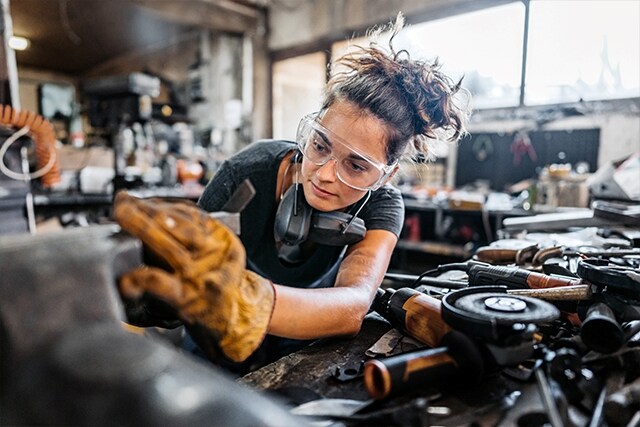 Una mecánica trabajando en un motor en un taller.