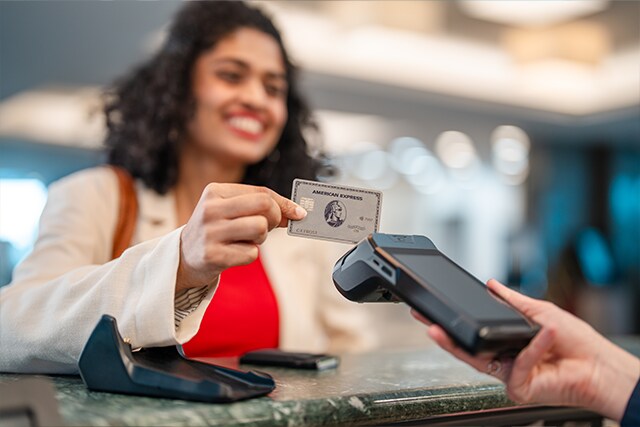 Mujer realizando un pago sin contacto con una tarjeta de crédito en una recepción.