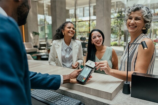 Grupo de amigas sonriendo en la recepción de un hotel.