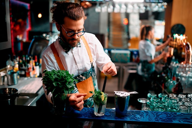 Un camarero en un bar de cócteles elegante preparando una bebida.