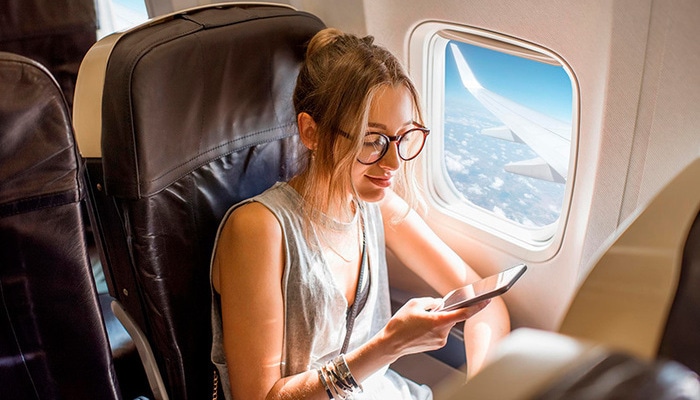 Mujer revisando su teléfon en un avión.
