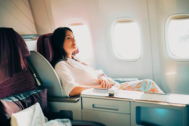 Mujer sentada en un asiento de Business Class en un avión.