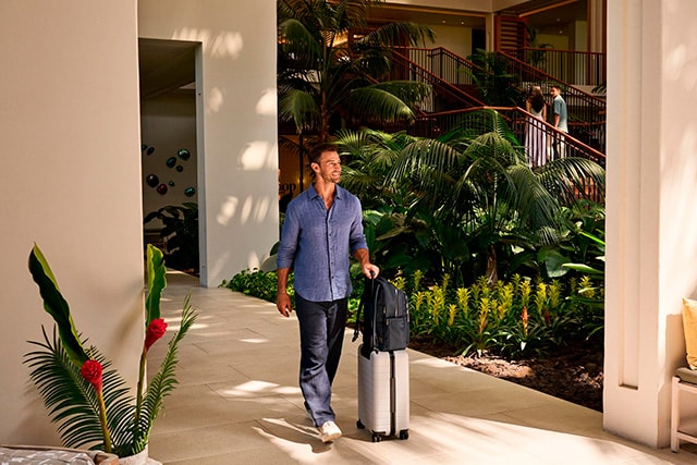 Un hombre saliendo de un hotel elegante con su equipaje.