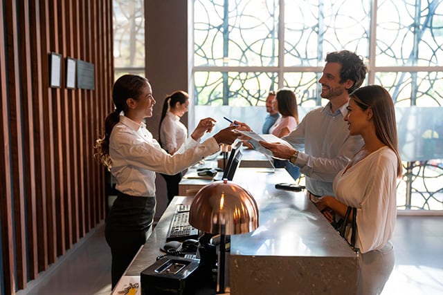 Una pareja registrándose en la recepción de un hotel.