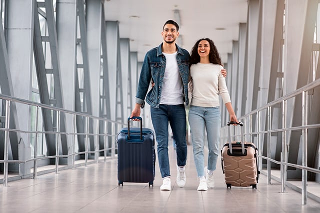 Una pareja caminando por un aeropuerto con sus maletas.
