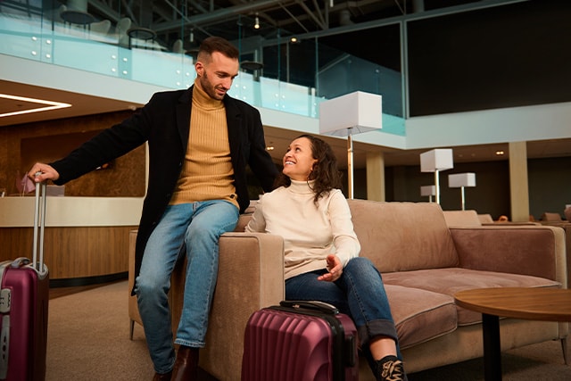Una pareja sentada en un sofá de una sala de espera del aeropuerto, mientras esperan su vuelo.