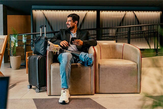Un hombre en una sala VIP de un aeropuerto revisando su teléfono celular.