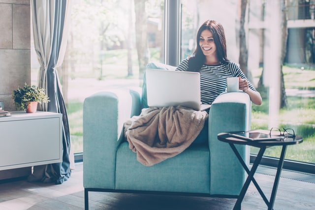 Mujer tomando café sentada en un cómodo sillón en casa.