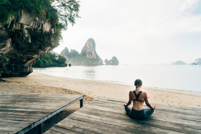 Joven haciendo yoga en el muelle de la playa de Krabi, Tailandia.