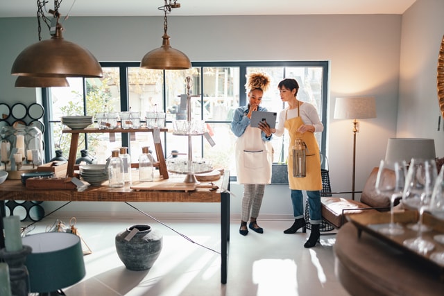 Dos mujeres en un comercio usando una tablet.