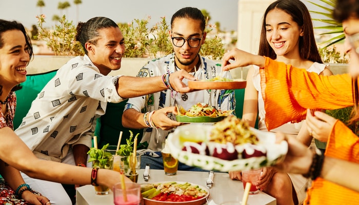 Amigos compartiendo comida en el restaurante mientras está de vacaciones juntos.