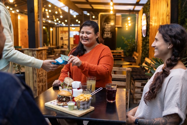 Amigas pagando la cena con una Tarjeta American express contactless.