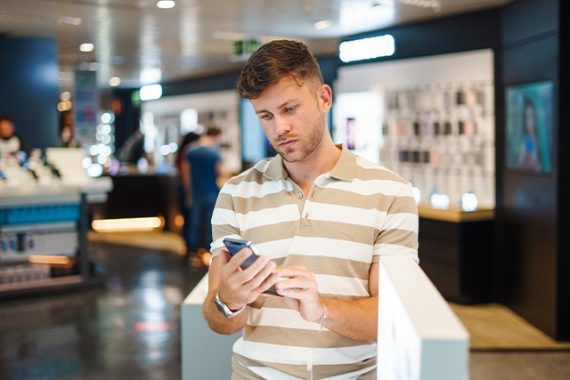 Hombre revisando su teléfono en una tienda departamental.