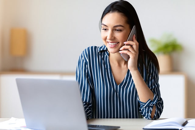 Mujer en casa con su teléfono celular buscando ayuda en línea.