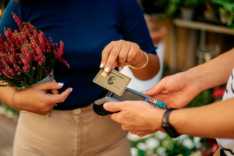 Una mujer pagando con su tarjeta Amex en una floristería local.