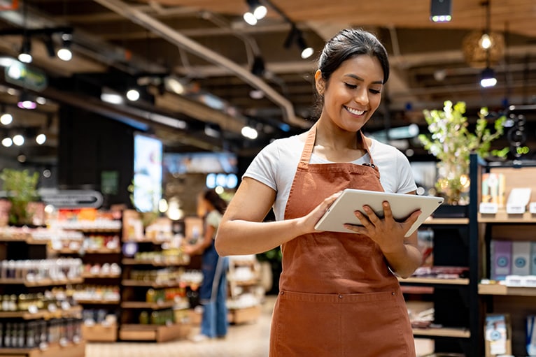 Mujer revisando una tableta en una tienda de alimentos.