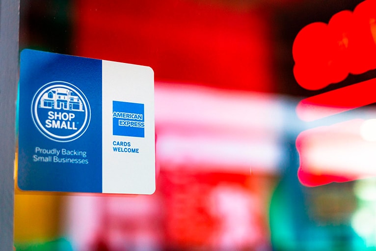 Adhesivo en el escaparate de una tienda con los logotipos de Amex y Shop Small.