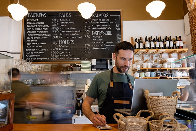 El dueño de una concurrida cafetería mirando la pantalla de una computadora.
