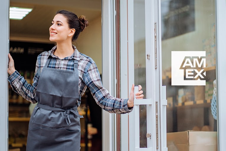 La propietaria de una tienda, en la puerta, con una pegatina del logotipo de Amex en el escaparate.