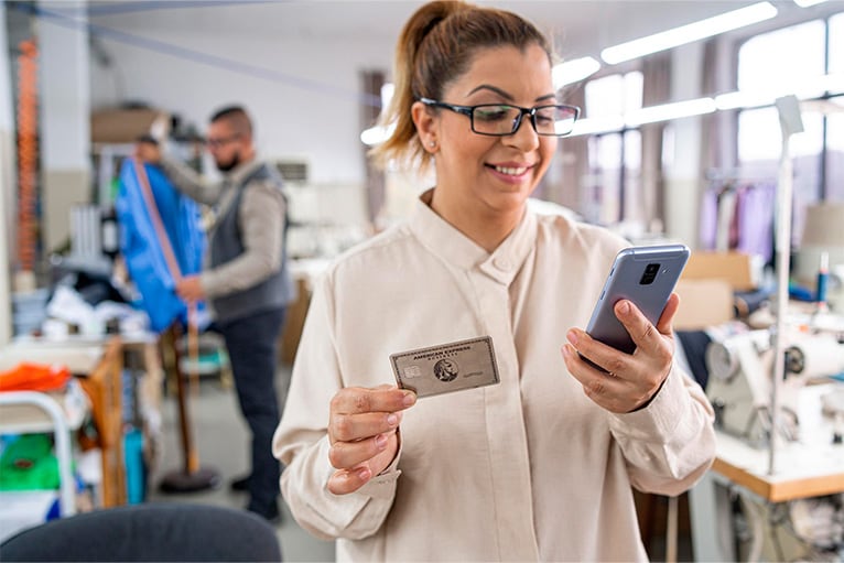 Empresaria en su taller, realizando una compra desde su teléfono celular.