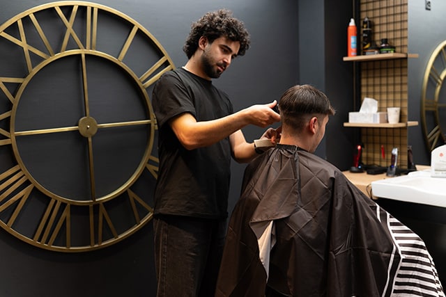 Un barbero cortando el pelo a un cliente en una barbería elegante.