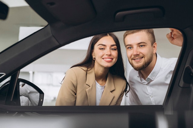 Una pareja mira el interior de un auto en una agencia.