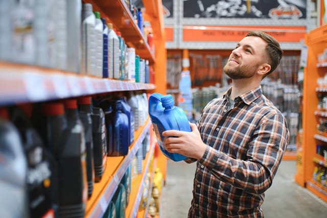 Un hombre examina lubricantes en una tienda de accesorios para automóviles.