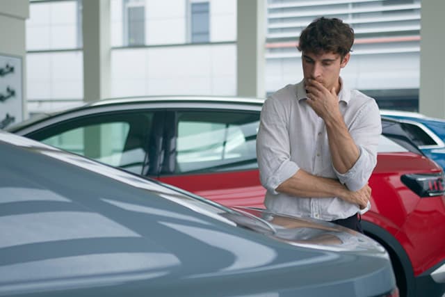 Un hombre mirando un auto nuevo en una agencia.