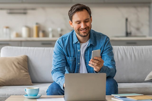 Un hombre en su casa mirando su celular.