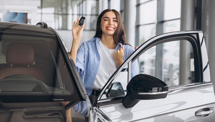 Una joven sonríe sosteniendo las llaves de su nuevo auto.
