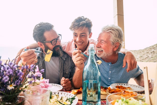 Padre abuelo e hijo comiendo juntos divirtiéndose..
