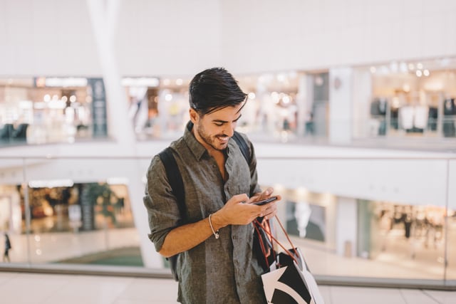 Hombre enviando mensajes de texto en el centro comercial.