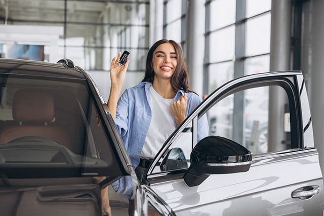 Mujer revisando un auto nuevo en una agencia de autos.