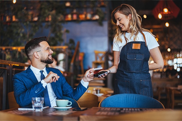 Hombre con traje pagando un café en una cafetería moderna.