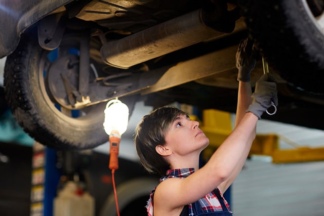Una mecánica reparando la transmisión de un carro.